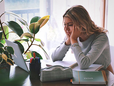 Female college student struggling to study on laptop