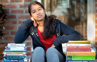 Female collge student with stacks of rented textbooks