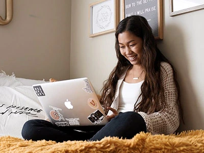 Student using Apple Macbook on dorm bed