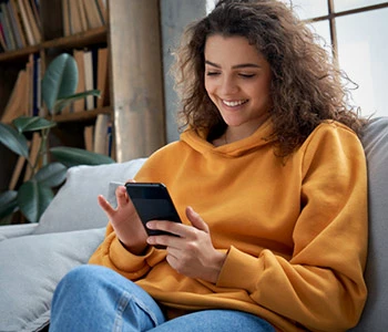 Female student scrolling on phone on couch