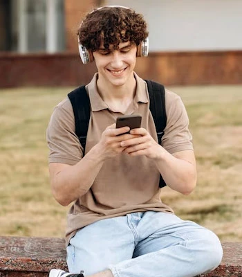 Male student using phone sitting on campus