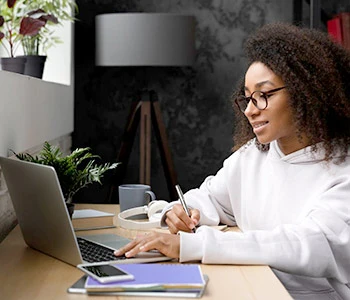 Black female student at desk using laptop for Online College Classes